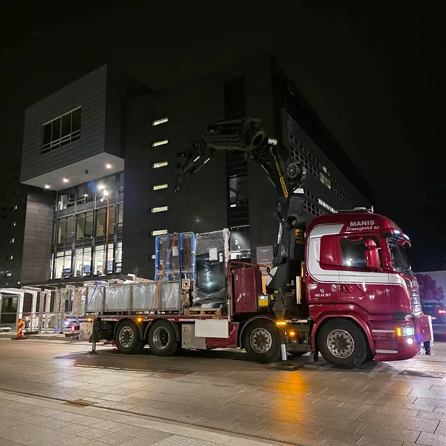 Rød kranbil utfører transportoppdrag om natten